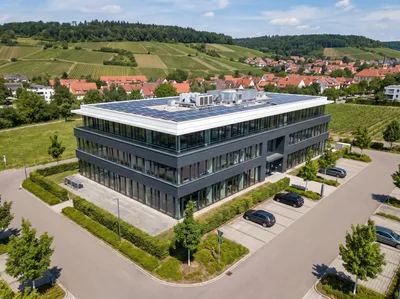 Drohnenaufnahme eines modernen Firmengebäudes aus der Luft, eingebettet in die Landschaft der Region